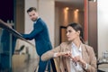 Young businesswoman in beige jacket feeling anoyed by her male colleague