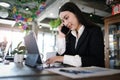 Young businesswoman in black suit talking on mobile phone and working with computer tablet while sitting at in modern cafe Royalty Free Stock Photo