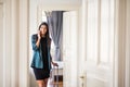 Young businesswoman on a business trip standing in a hotel room, using smartphone. Royalty Free Stock Photo