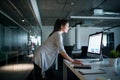 Young businesswoman with computer standing in an office, working.