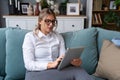 Young businesswoman cryptocurrency trader sitting in home office working on tablet while sitting on sofa. Freelance female global Royalty Free Stock Photo