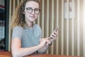 Young businesswoman in glasses sits and uses a smartphone. Girl, student working, blogging, chatting, learning online Royalty Free Stock Photo