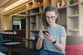 Young businesswoman in glasses sits, uses smartphone, working. Royalty Free Stock Photo