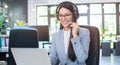 Young businesswoman with headset working on laptop in modern office Royalty Free Stock Photo