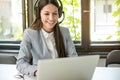 Young businesswoman with headset working on laptop in modern office Royalty Free Stock Photo