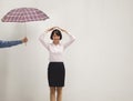 Young businesswoman with her hand above head, co-worker giving her umbrella Royalty Free Stock Photo