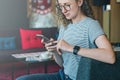 Young businesswoman hippest sits on sofa in hotel lobby and uses smartphone.Girl chatting,working,learning,shopping Royalty Free Stock Photo