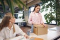 Young businesswoman holding box of personal belongings about to leave office after quitting job