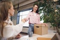 Young businesswoman holding box of personal belongings about to leave office after quitting job