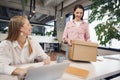 Young businesswoman holding box of personal belongings about to leave office after quitting job