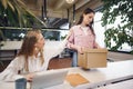 Young businesswoman holding box of personal belongings about to leave office after quitting job