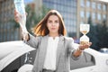 Young businesswoman holding empty bottle and hourglass outdoors. Time management concept