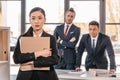 Young businesswoman holding folder and businessmen standing behind Royalty Free Stock Photo