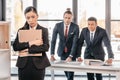 Young businesswoman holding folder and businessmen standing behind Royalty Free Stock Photo