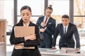 Young businesswoman holding folder and businessmen standing behind Royalty Free Stock Photo