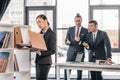 Young businesswoman holding folder while colleagues standing and looking behind Royalty Free Stock Photo