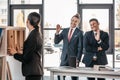 Young businesswoman holding folder while colleagues standing and looking behind Royalty Free Stock Photo