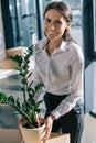 young businesswoman holding potted plant and smiling at camera Royalty Free Stock Photo