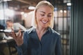 Young businesswoman laughing and talking on speakerphone in an o