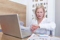 Young businesswoman looking at display of wristwatch and managing time while checking email on laptop.Freelancer with watch on