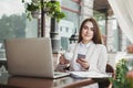 Young businesswoman outdoors using smartphone and drinking coffee