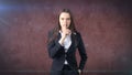 Young businesswoman portrait in suit standing and finger up near her lips with hush sign, background with copyspace. Royalty Free Stock Photo