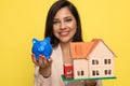 Young businesswoman presenting piggy bank and house model Royalty Free Stock Photo