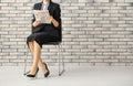 Young businesswoman reading newspaper against brick wall Royalty Free Stock Photo