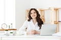 Young businesswoman or secretary sitting at desk and working. Smiling and looking at camera