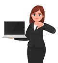 Young businesswoman showing a new brand laptop and making thumb down gesture sign. Person holding portable computer.
