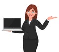 Young businesswoman showing a new brand laptop and presenting hand gesture to copy space. Person holding portable computer. Royalty Free Stock Photo