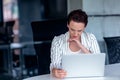 A young businesswoman sits behind her laptop computer frowning with her head in her hands because of a problem at work Royalty Free Stock Photo