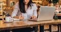 Businesswoman is sitting in cafe at table in front of laptop, making notes in notebook, working.Student learning online. Royalty Free Stock Photo