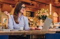 Businesswoman is sitting in cafe at table, working on laptop. Hipster girl blogging, browsing internet, checking email.