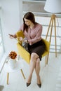 Young businesswoman sitting on a chair and holding tablet in her hands Royalty Free Stock Photo