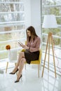 Young businesswoman sitting on a chair and holding tablet in her hands Royalty Free Stock Photo