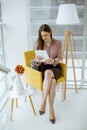 Young businesswoman sitting on a chair and holding tablet in her hands Royalty Free Stock Photo