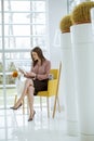 Young businesswoman sitting on a chair and holding tablet in her hands Royalty Free Stock Photo