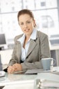 Young businesswoman sitting by desk in office Royalty Free Stock Photo