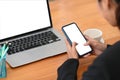 Young businesswoman sitting in front of computer laptop and using mobile phone. Royalty Free Stock Photo