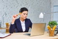 Young businesswoman sitting with laptop at desk against brick wall in office Royalty Free Stock Photo