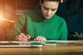 Young businesswoman sitting at table and fills out an application. On table is smartphone and tablet computer.