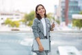 Young businesswoman smiling while texting on phone holding laptop outside Royalty Free Stock Photo