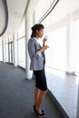 Young Businesswoman Standing In Corridor Of Modern Office Building Drinking Coffee Royalty Free Stock Photo