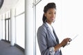 Young Businesswoman Standing In Corridor Of Modern Office Building Using Tablet Computer Royalty Free Stock Photo