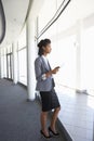 Young Businesswoman Standing In Corridor Of Modern Office Building Using Tablet Computer Royalty Free Stock Photo