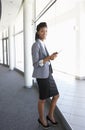 Young Businesswoman Standing In Corridor Of Modern Office Building Using Tablet Computer Royalty Free Stock Photo