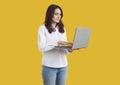 Young businesswoman standing isolated on yellow background and using laptop computer Royalty Free Stock Photo