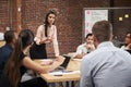 Young Businesswoman Standing And Leading Office Meeting Around Table Royalty Free Stock Photo