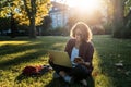 Young businesswoman student working on her notebook in park. Freelancer female sitting on grassy lawn using laptop computer with Royalty Free Stock Photo